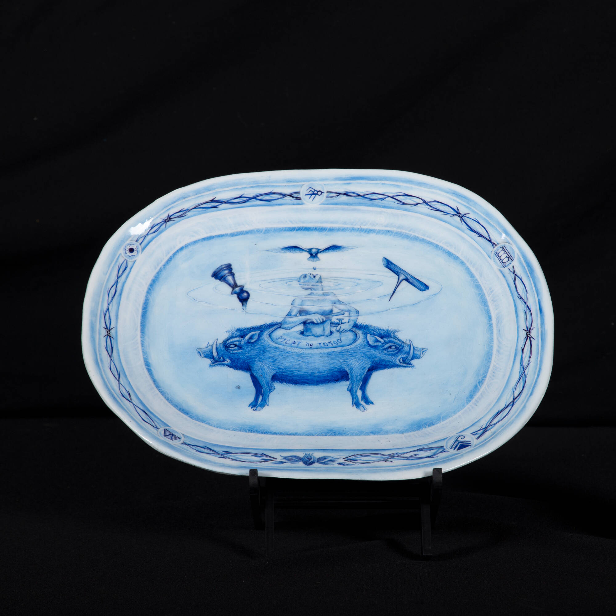 Photograph of a ceramic plate of a blue and white two-headed boar image.